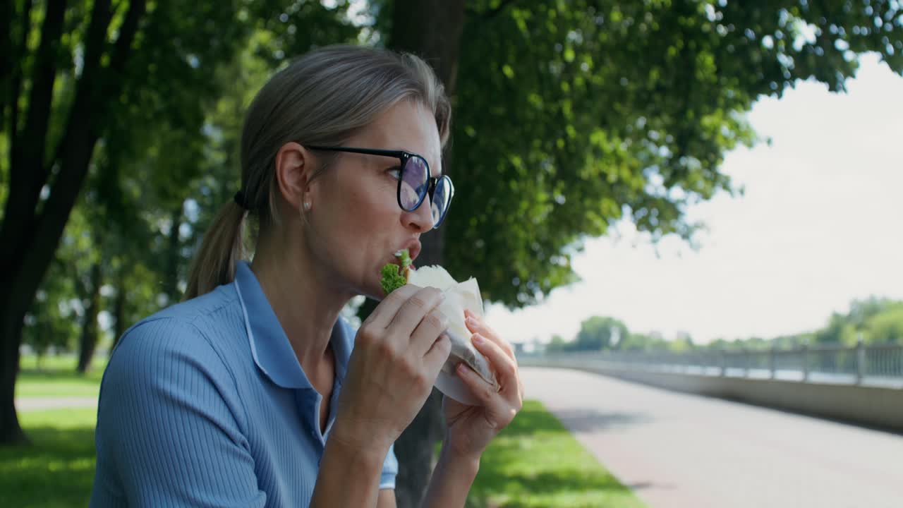 Donna che mangia un panino al parco