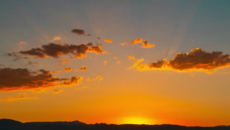 the sun sets behind the mountains in golden splendor as another day comes to an end - static time lapse with