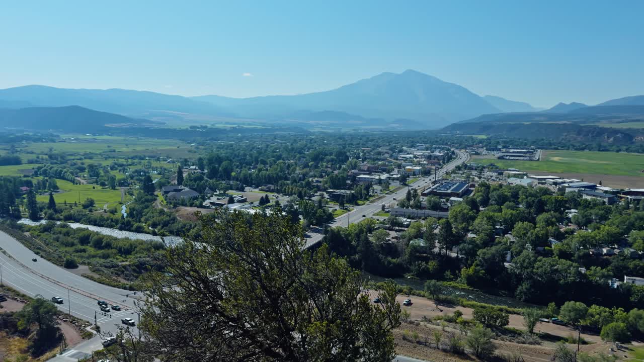 Expansive establishing overview of Carbondale valley with distant mountains under soft daylight, panoramic pan above roads and neighborhood