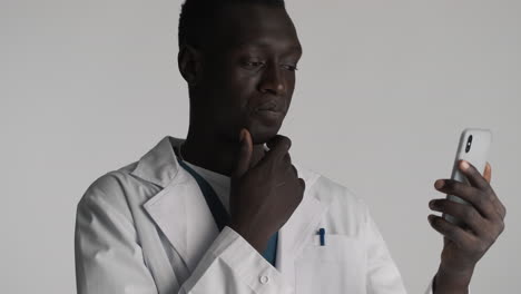 thoughtful african american doctor on grey background.