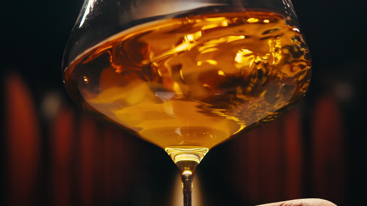 Orange or white wine bottle and glass against a sunset in a peaceful vineyard, pouring of ecological natural wine.