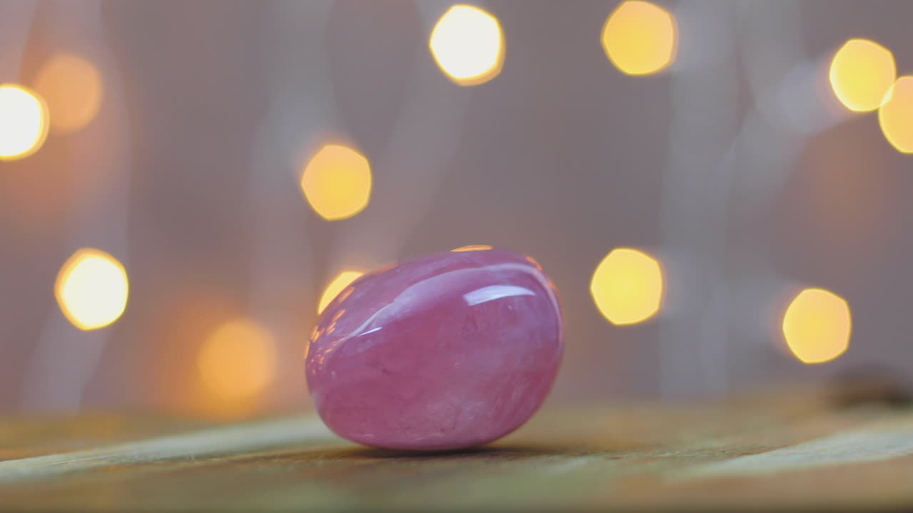 me encanta curar la piedra preciosa de cuarzo rosa en una mesa de madera con luces