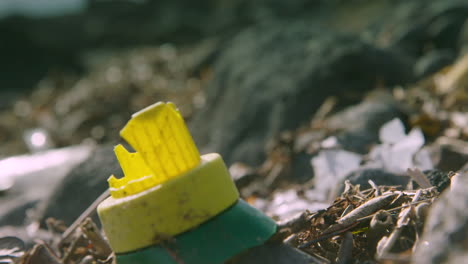 focus pull from plastic rubbish to a broken plastic bottle on the beach