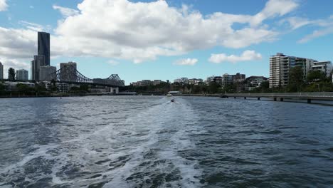 Fliegen-Entlang-Des-Brisbane-Riverwalk-In-Richtung-Der-Story-Bridge-Mit-Booten-In-Der-Ferne