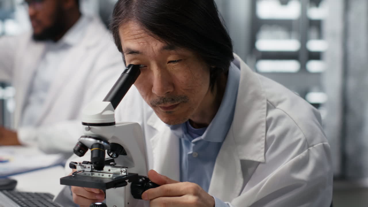 Vertical video Clinical microbiologist examining microscope glass slide in laboratory to view cells