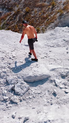 brutal strong bodybuilder posing outdoor. photoshoot in a quarry. outdoor sports concept. aerial view. handsome strongman walks up a quarry. white landscape. vertical video