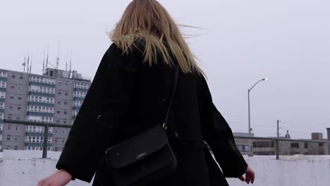 Plano-Medio-De-Una-Hermosa-Mujer-Rubia-Equilibrándose-Durante-Una-Tormenta-De-Nieve-En-Canadá