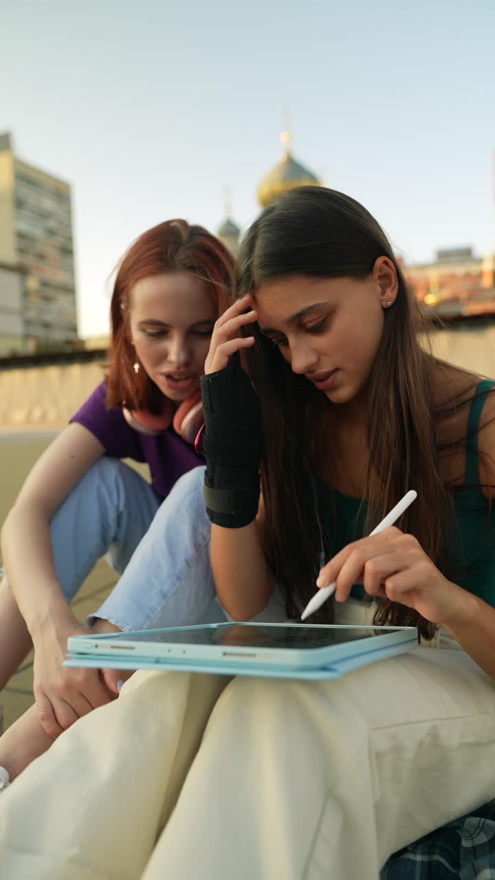 Due ragazze adolescenti che lavorano insieme su un tablet all'aperto.