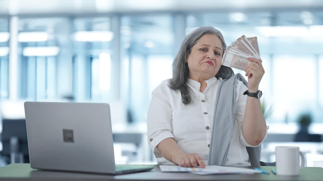 una mujer de negocios india segura de sí misma usando el dinero como ventilador.