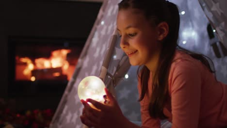 happy caucasian girl playing with snow globe at christmas