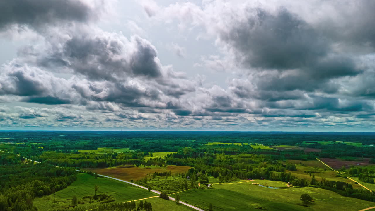 Panoramic aerial view of white clouds drifting over a green landscape