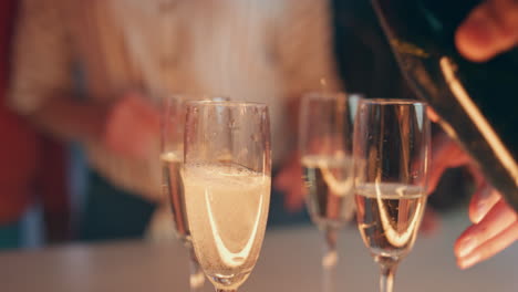 bartender hand pouring champagne glasses at terrace closeup. friends toasting