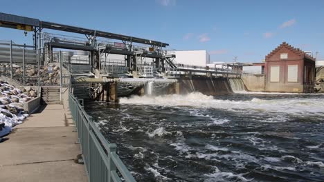 Walking-along-sidewalk-towards-river-dam-with-water-flowing