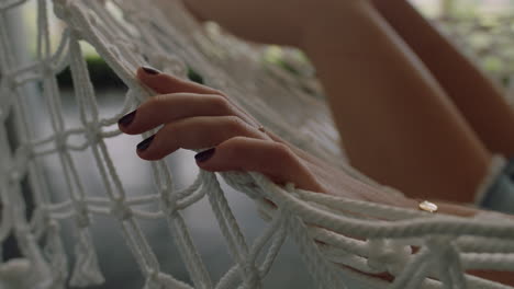 close up hand of woman in hammock gently moving fingers sleeping comfortable on holiday in vacation resort swaying peacefully on lazy summer day