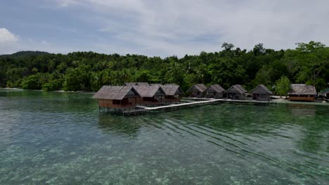 Raja-Ampat-Luftaufnahme-Des-Strandes,-Des-Riffs-Und-Der-Hütten-An-Einem-Heißen,-Sonnigen-Tag