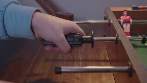 A young boy plays miniature table football game