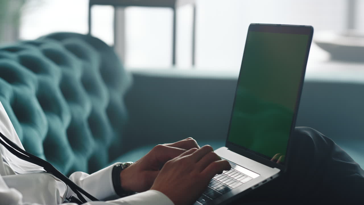 Male hands typing on laptop with green screen. Worker using laptop computer