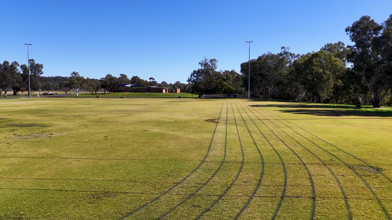 Inquadratura ampia e statica di una pista da corsa in erba e di un campo sportivo a Gunnedah, Australia