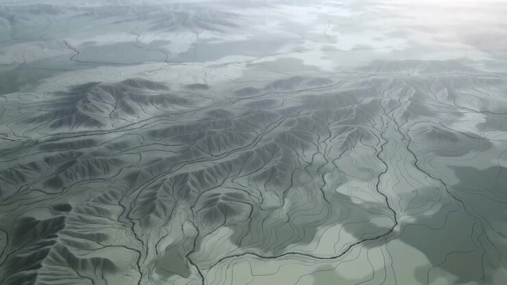 Aerial middle-sequence pan over eroded ridge and winding dry riverbeds revealing layered terraces