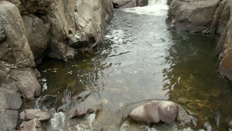 pan upwards over river to waterfall in canyon in colorado