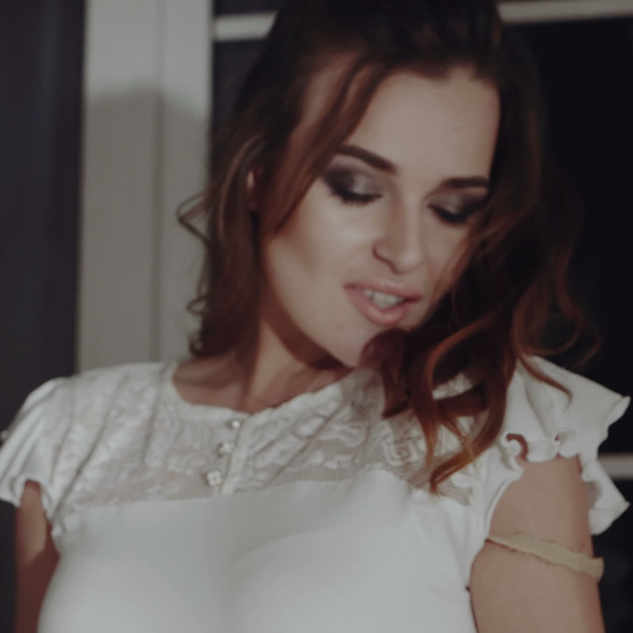 Sexy beautiful brunette girl in white underclothes posing by the big window. Fashion portrait of model indoors.