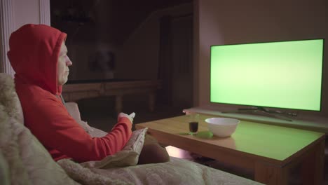 man in the hood watches tv , sits on the couch at home in the evening, chromakey