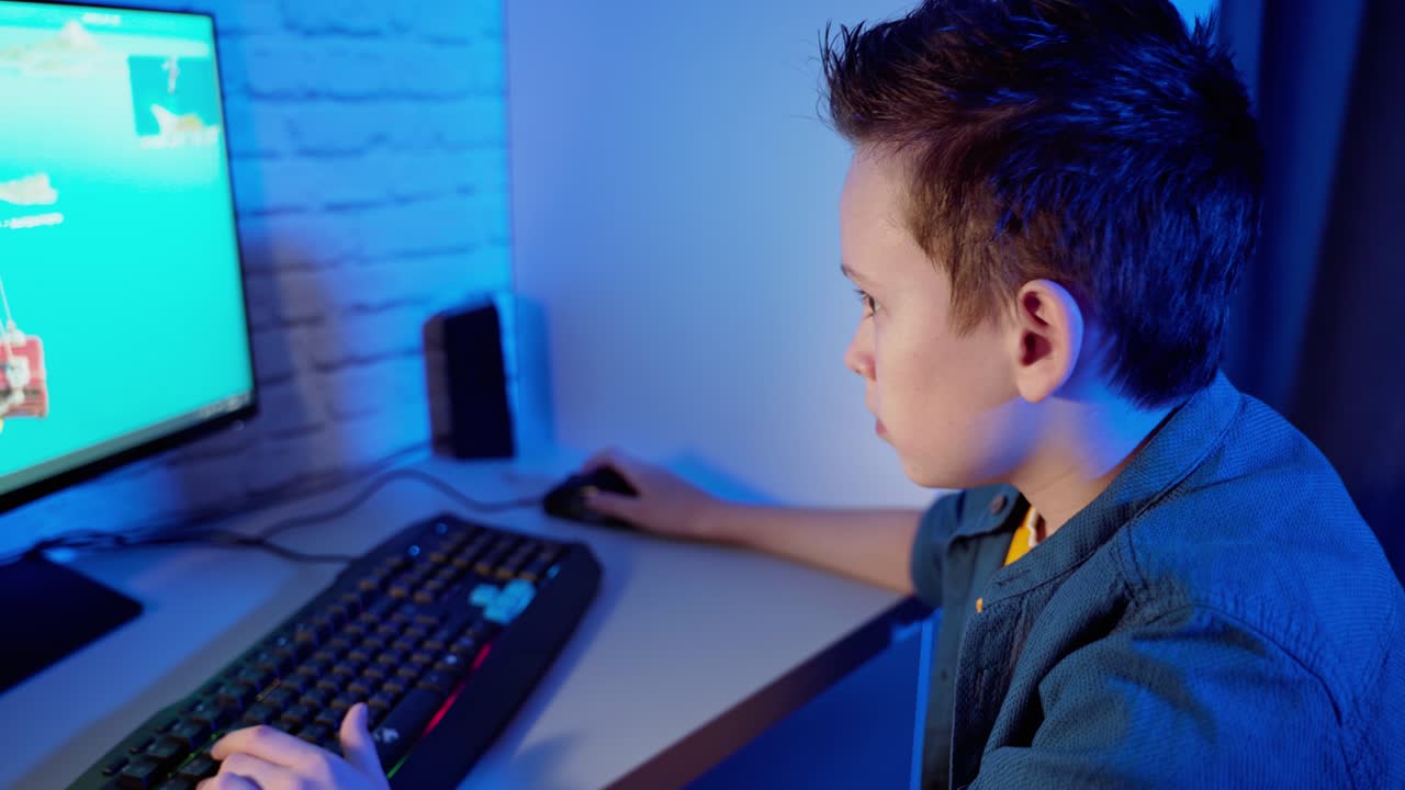 Boy playing computer game at home. Teenager sitting in front of the screen concentrated on virtual reality of the game in the room.