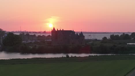 Drohnenansicht-Des-Schlosses-Muiderslot-Mit-Atemberaubendem-Sonnenuntergang-Im-Hintergrund,-Luftaufnahme