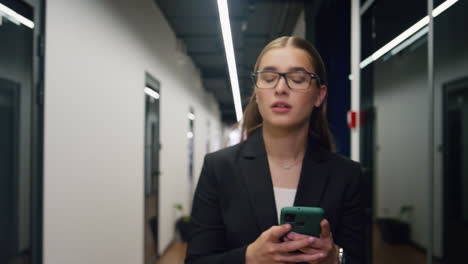 el gerente de la oficina enviando mensajes de texto al teléfono inteligente caminando por el pasillo de cerca. llamada amigable del empleado