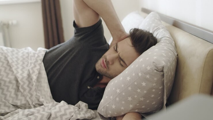 Sleepy man hating alarm clock noise