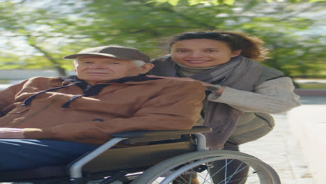 portrait of woman and senior man in wheelchair in park