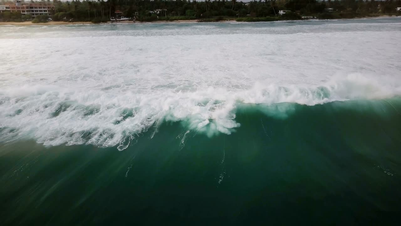 드론 카메라는 거대한 파란 바다 거품 파도가 열대 나무와 집으로 아름다운 이국적인 리조트 해안으로 서두르는 따라