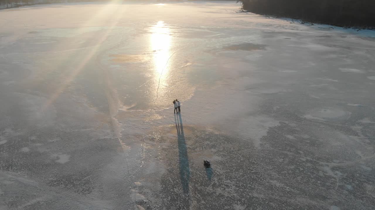 pareja caminando en un lago congelado durante el atardecer