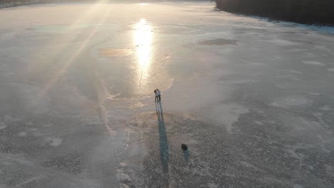 Couple-walking-in-a-frozen-lake-during-sunset