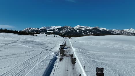 Coche-Aparcado-En-Pista-Nevada-Con-Charco-En-Stanley,-Idaho