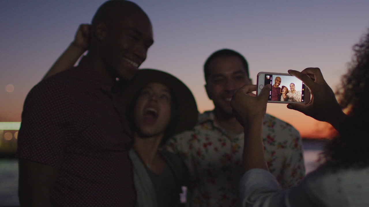 Group Of Friends Posing For Photo In Front Of Manhattan Skyline At Dusk