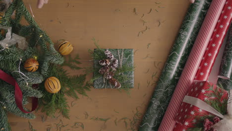 Ein-Top-Down-Plan.-Der-Tisch-Mit-Den-Dekorationen-Ist-Vollständig-Sichtbar.-Weihnachtsgeschenk-In-Bastelpapier-Verpackt-Auf-Einem-Holztisch.-Verbandsband-Und-Gebundene-Schleife.