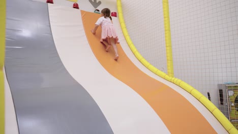 little girl playing on a soft play slide at indoor playground