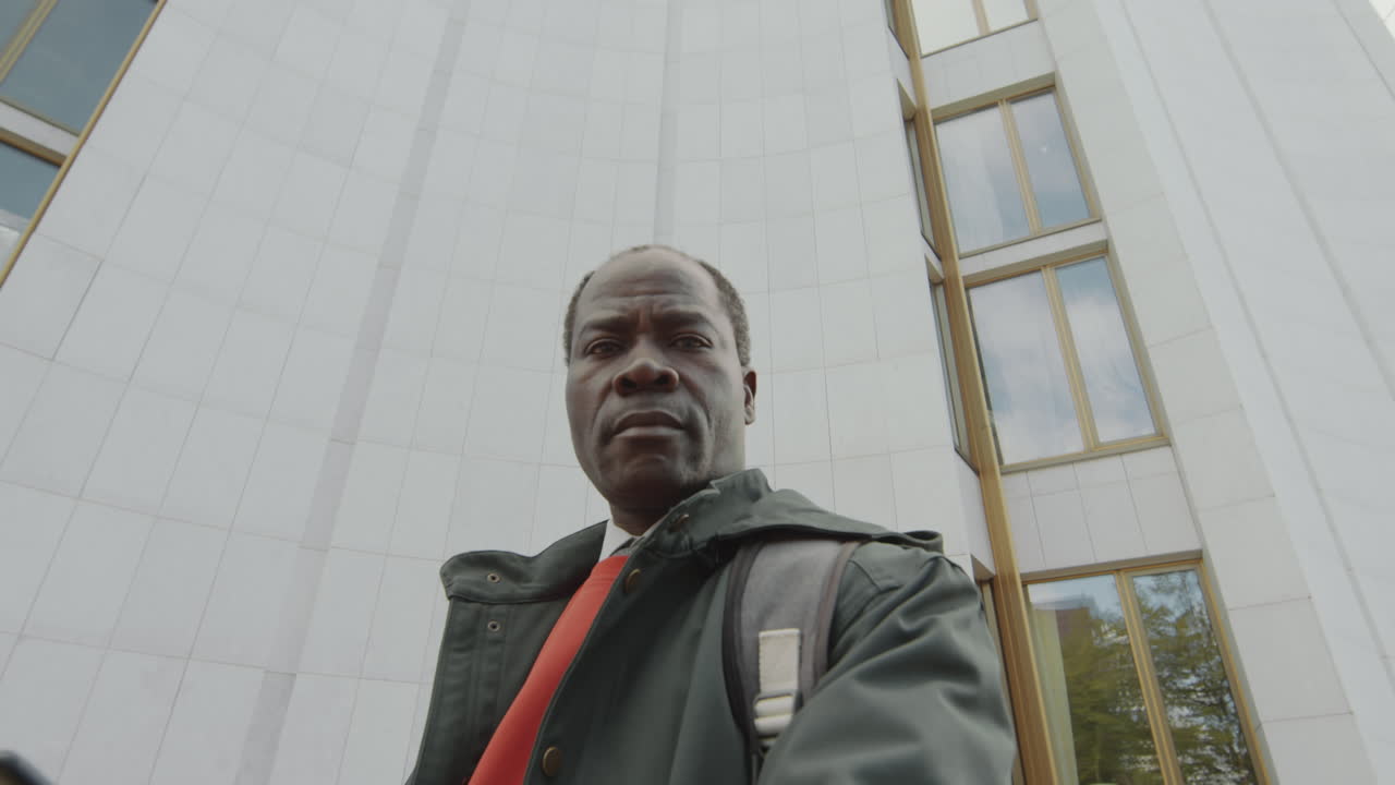 Low-angle portrait of a serious man in front of a modern building