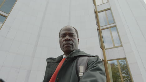 low-angle portrait of a serious man in front of a modern building