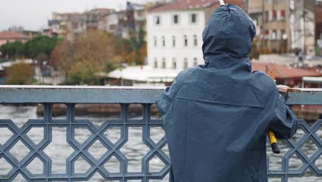 man fishing from a bridge in a city