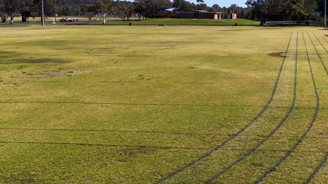 Ampia inquadratura statica di un campo sportivo in erba con corsie di corsa segnate a Gunnedah, Australia