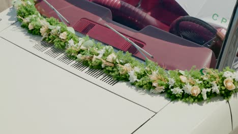 white car adorned with delicate floral garland for a wedding celebration