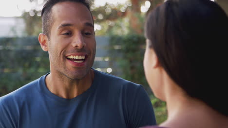 smiling hispanic couple talking and laughing in garden at home