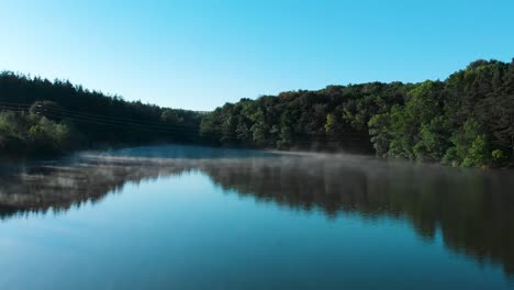 foggy lake and forest after sunrise - panning shot over water