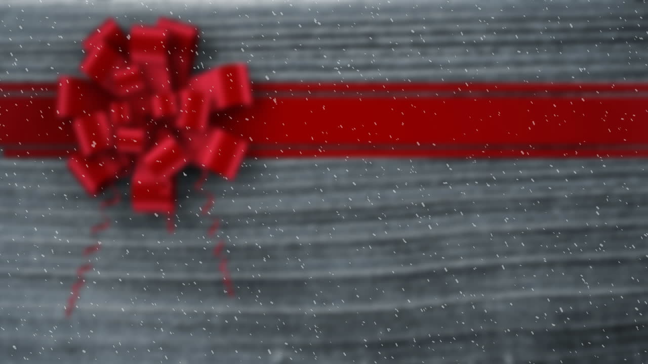 Animazione di neve che cade su nastro regalo di Natale su legno