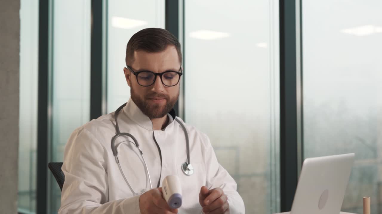 Un medico in camice misura la temperatura del paziente con un termometro a distanza.