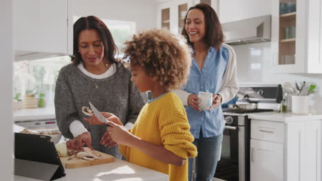 Niña-Afroamericana-Preadolescente-Preparando-Comida-En-La-Cocina-Con-Su-Abuela,-Su-Madre-Mirando