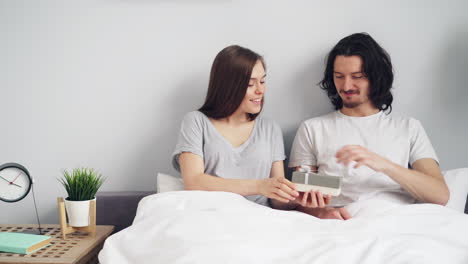 couple exchanging gifts in bed