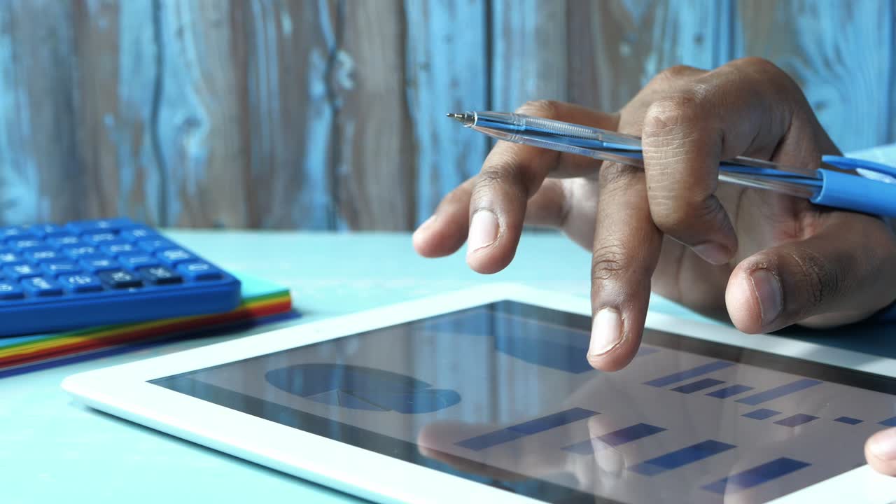 Person Using Tablet with Graphs and Calculator